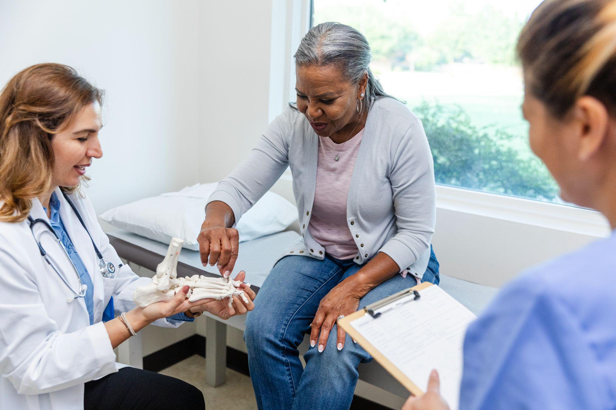 An older woman meeting a doctor and nurse to learn about bone health.